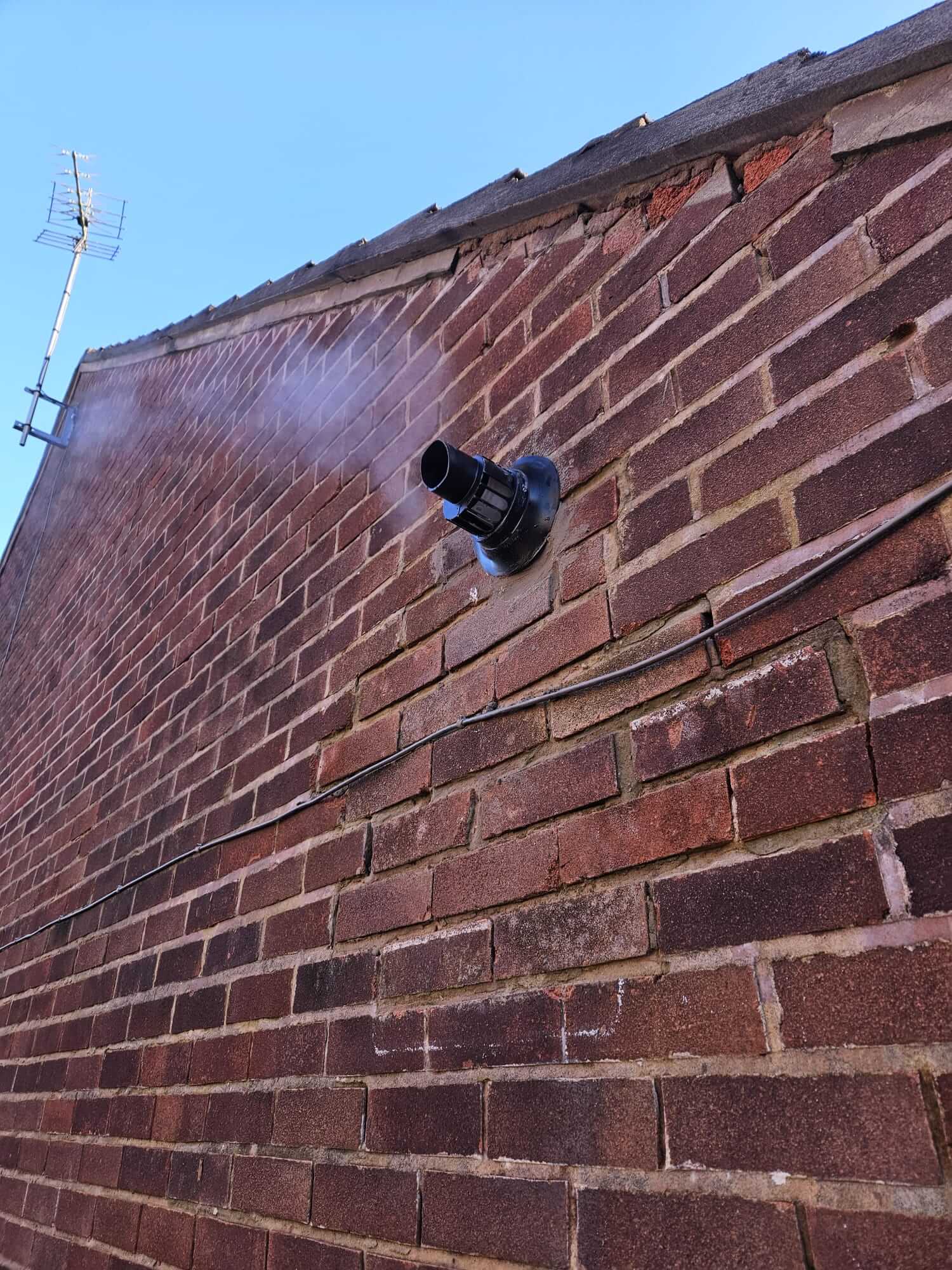 Boiler flue terminal through an exterior red-brick wall
