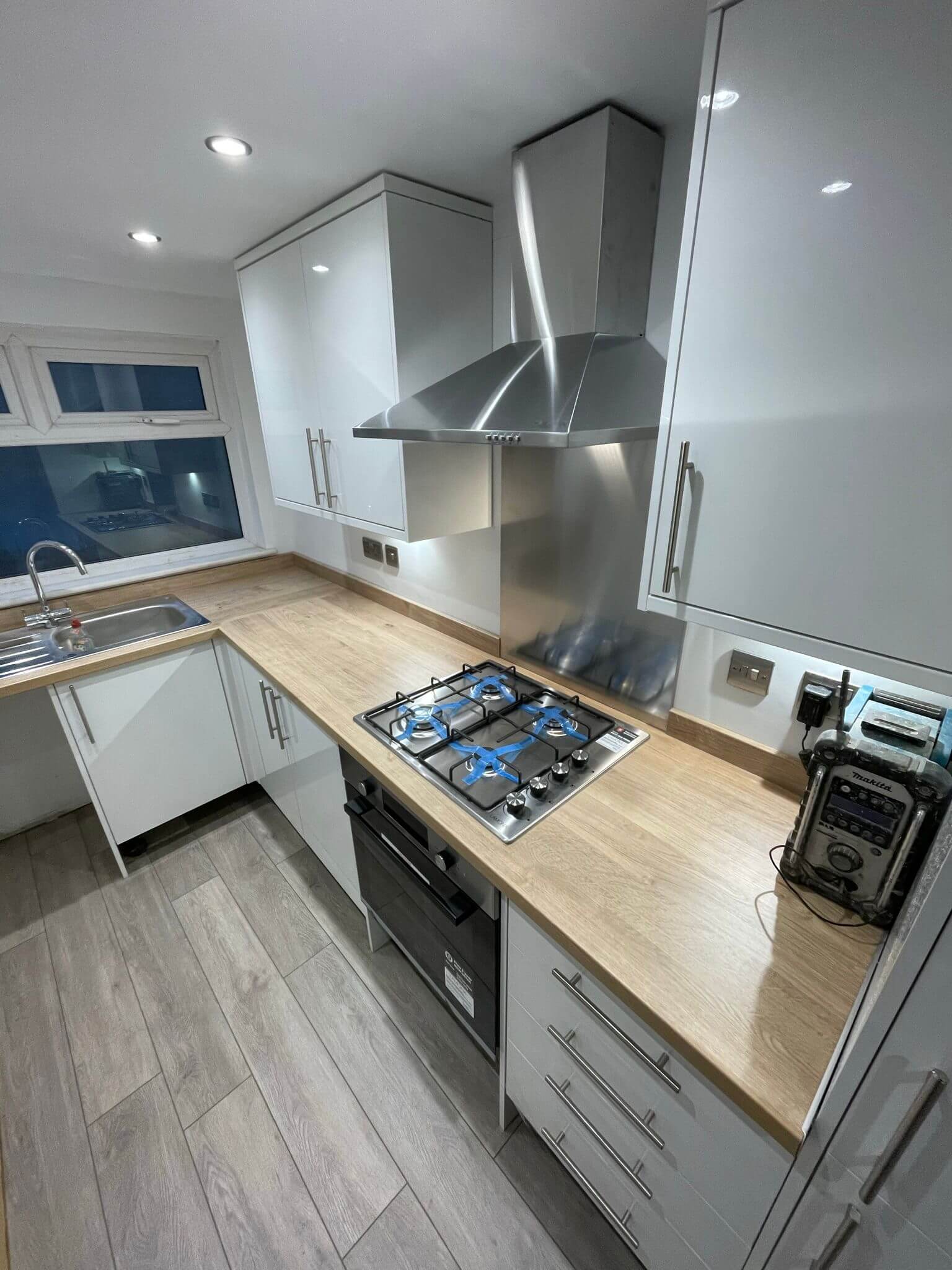 Gas hob and stainless steel extractor in a white kitchen with wood-effect worktops