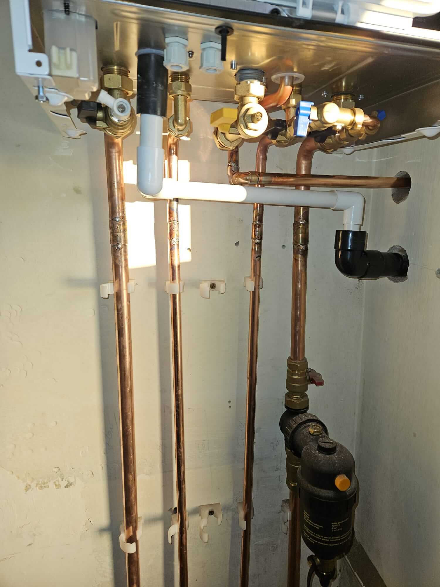 Copper pipework and magnetic filter beneath a wall-mounted boiler